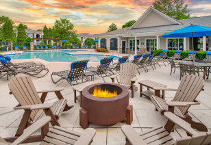 Long view of swimming pool with lounge chairs and poolside firepit surrounded by armchairs at MAA Cornelius luxury apartments in Cornelius, NC