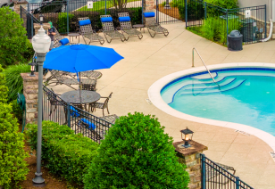 Side view of swimming pool with entrance steps and metal handrails, surrounded by lounge chairs and lush greenery at MAA Cornelius luxury apartments in Cornelius, NC