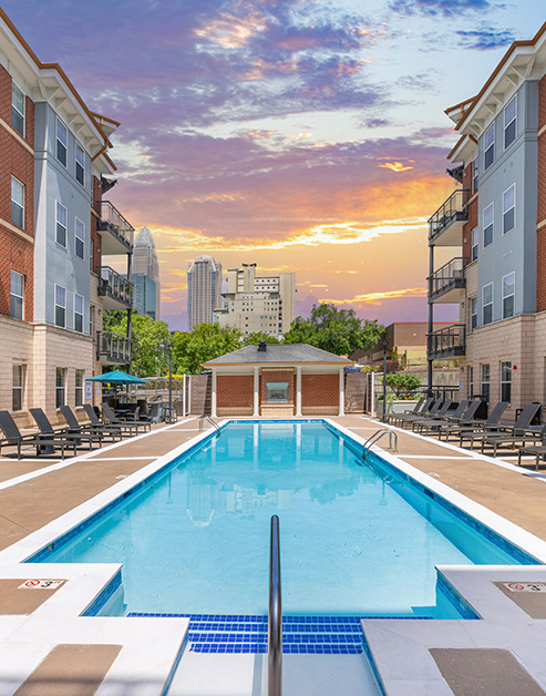 Resort-style swimming pool surrounded by lounge chairs situated next to the apartment complex at MAA Enclave luxury apartments in Charlotte, NC