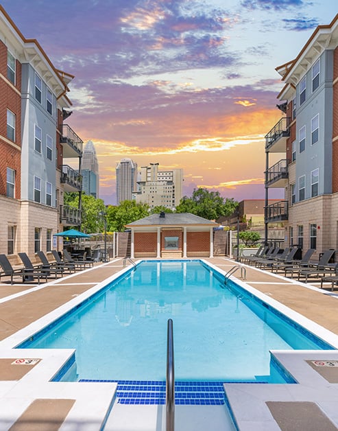 Resort-style swimming pool surrounded by lounge chairs situated next to the apartment complex at MAA Enclave luxury apartments in Charlotte, NC