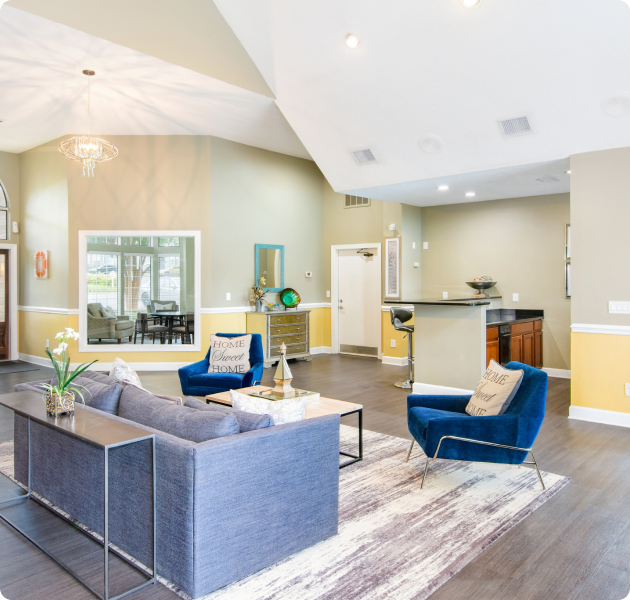 Community center with wood floors, kitchen area with bartop counter, and lounge area with modern couch and arm chairs with coffee table at MAA Fifty-One luxury apartments in Matthews, NC