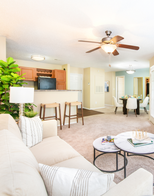 Model living room area next to kitchen with bartop counter, coffee table and modern-style white couch at MAA Fifty-One luxury apartments in Matthews, NC