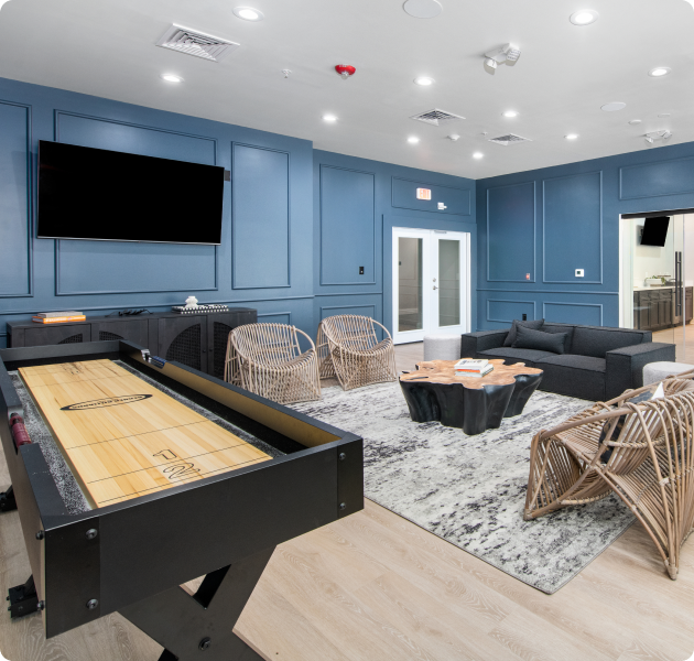 Community lounge area with wall mounted TV and multiple sitting areas next to a shuffleboard table at MAA Gateway luxury apartments in Charlotte, NC