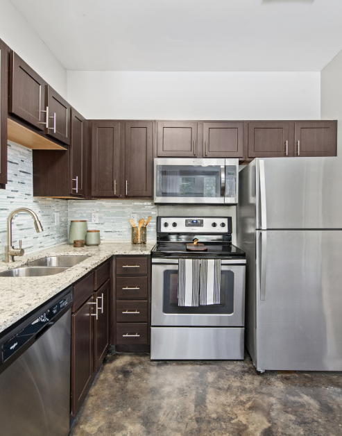 Modern-style kitchen with dark brown cabinets, light-toned countertop and double sink with stainless-steel appliances on hard floors at MAA Gateway luxury apartments in Charlotte, NC