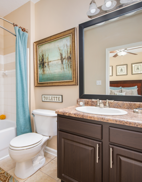 Modern bathroom with a large vanity mirror, brown granite countertop with dark brown cabinets and tile floors at MAA Huntersville luxury apartments in Huntersville, NC