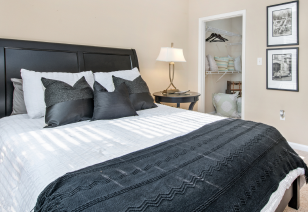Model bedroom queen bed with wooden headboard with walk-in closet at MAA Huntersville luxury apartments in Huntersville, NC