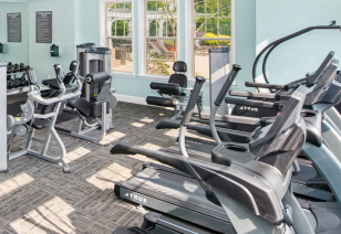 Fitness center with treadmills and weight machines next to large windows at MAA Huntersville luxury apartments in Huntersville, NC
