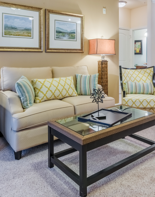 Light-toned living room with wall paintings above the couch with dark brown coffee table at MAA Huntersville luxury apartments in Huntersville, NC