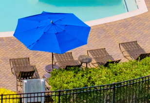 Close up aerial view of poolside lounge chairs with umbrella at MAA Huntersville luxury apartments in Huntersville, NC