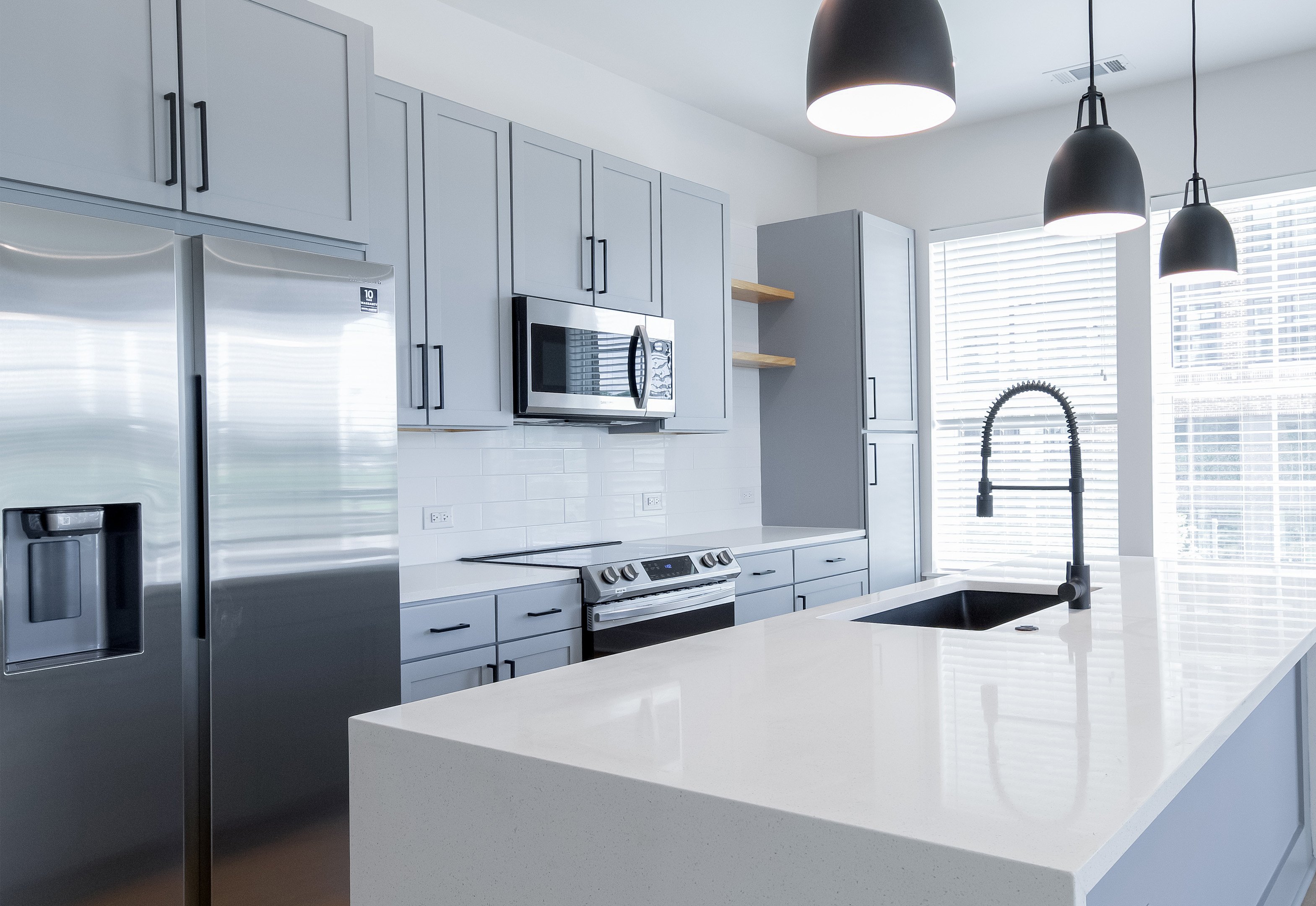 Side view of modern kitchen with white pristine countertop, light gray cabinets and stainless-steel appliances at MAA LoSo luxury apartments in Charlotte, NC
