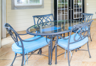 Close up of clubhouse blue wrought iron glass patio table with chairs next to French doors and tile floors at MAA Matthews Commons luxury apartments in Matthews, NC