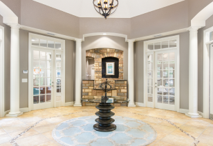Community clubhouse and leasing office foyer with a center round table, double French doors and ornate tile flooring at MAA Matthews Commons luxury apartments in Matthews, NC