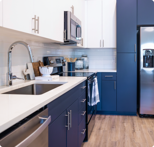 A modern kitchen featuring blue and white cabinets, stainless steel refrigerator, electric stove with wood flooring at MAA Optimist Park luxury apartments in Charlotte, NC