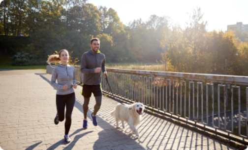 Two people running with a dog