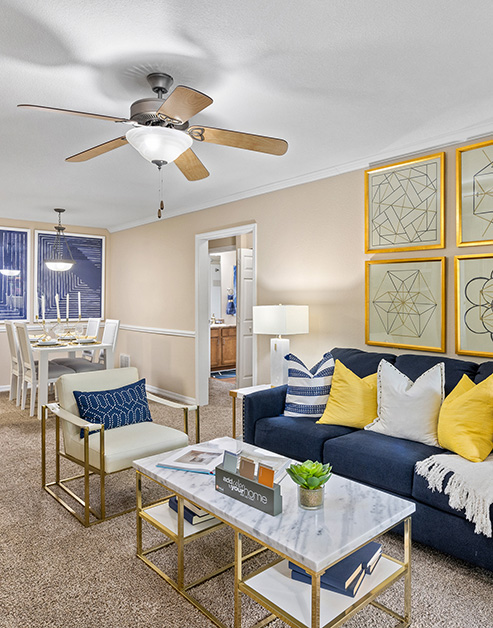 Model living room with wall paintings, a dark couch with pillows and marble top coffee table at MAA Prosperity Creek luxury apartments in Charlotte, NC