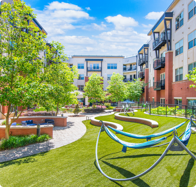 Community sunny courtyard with grass, lounge hammocks and multiple sitting areas with lush trees at MAA Reserve luxury apartments in Charlotte, NC