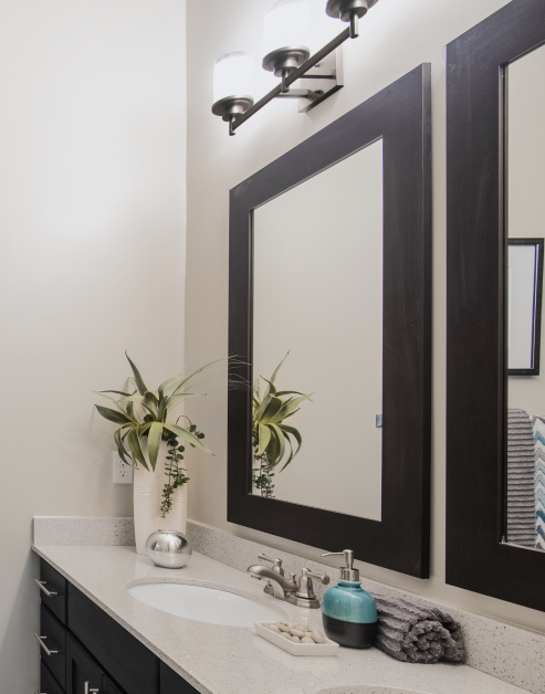 Bathroom with framed vanity mirror, light-colored counter top with sink and dark cabinets at MAA Reserve luxury apartments in Charlotte, NC