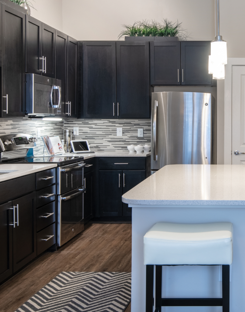 Modern kitchen with black cabinets, stainless steel appliances and a white countertop kitchen island with wood flooring at MAA Reserve luxury apartments in Charlotte, NC