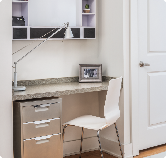 Close up of an apartment with a built-in office workspace and chair with a table lamp and cabinet with drawers at MAA South Line luxury apartments in Charlotte, NC