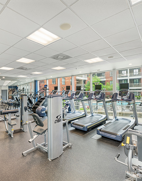 Fitness center with treadmills and various workout machines next to large picture windows views of pool at MAA South Line luxury apartments in Charlotte, NC