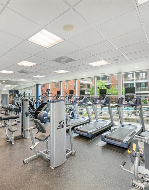 Fitness center with treadmills and various workout machines next to large picture windows views of pool at MAA South Line luxury apartments in Charlotte, NC