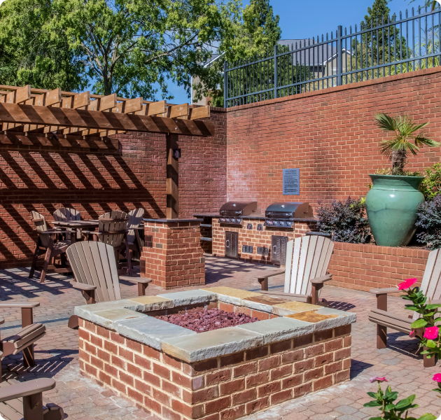 Community outdoor grill stations, patio tables and chairs next to fire pit surrounded by chairs at MAA South Park luxury apartments in Charlotte, NC