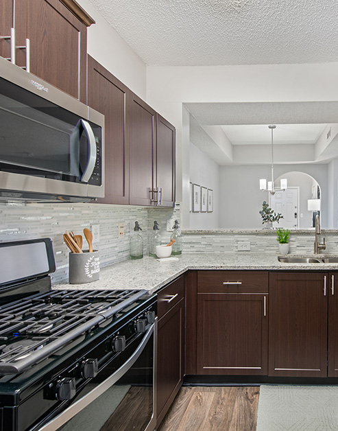Upscale kitchen with dark brown cabinets, granite counter top, modern appliances and wood floors at MAA South Park luxury apartments in Charlotte, NC