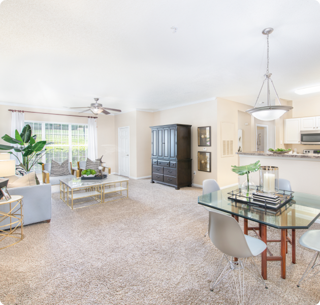 Apartment with large open space between dining area and living room with couch and coffee table next a large picture window with curtains at MAA University Lake luxury apartments in Charlotte, NC