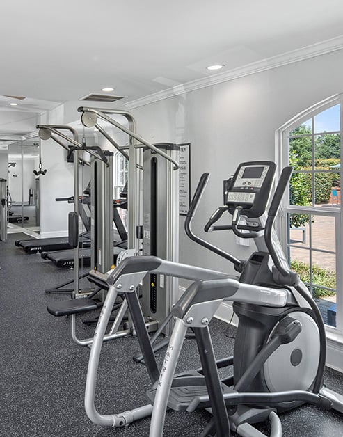 Fitness center with a variety of workout equipment next to large picture windows at MAA University Lake luxury apartments in Charlotte, NC