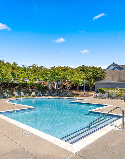 Resort-style pool surrounded by lounge chairs at MAA University Lake luxury apartments in Charlotte, NC