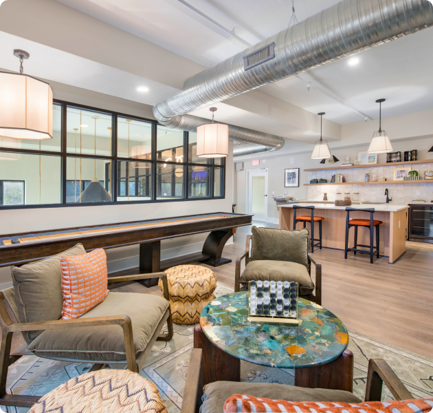 Community center with coffee bar, multiple sitting areas with shuffle board on wood floors at MAA Uptown luxury apartments in Charlotte, NC