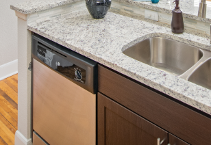 Close up of kitchen bar top counter with double sink with a dish washer at MAA Uptown luxury apartments in Charlotte, NC