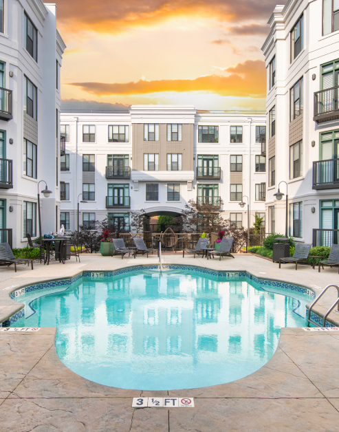 Resort-style pool with entrance steps and metal handrails on either side with lounge chairs situated next to the apartment complex at MAA Uptown luxury apartments in Charlotte, NC