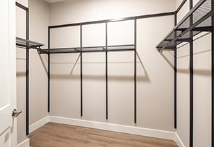 Empty walk-in closet with off-white walls and black metal shelving and light-colored hardwood floors at MAA Nixie luxury apartments in Durham, NC