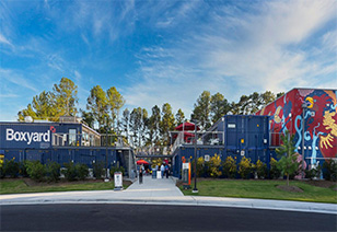 Entrance of sports area with box yard facility, foreground with a paved street and sidewalk with a grass area at MAA Nixie luxury apartments in Durham, NC