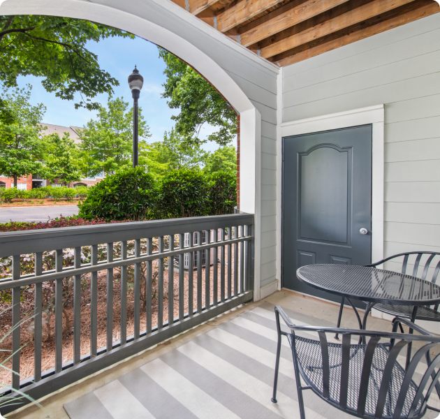 Spacious apartment porch with patio furniture and a wood beam ceiling with stylish archway opening and a storage unit at MAA Providence luxury apartments in Raleigh, NC.