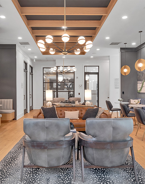 Modern community clubhouse with chandelier on a wooden slatted ceiling with multiple sitting areas on wood floors at MAA Vale luxury apartments in Raleigh, NC
