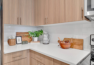 Corner view of kitchen with light-colored wood cabinets and white countertops with drawers at MAA Vale luxury apartments in Raleigh, NC