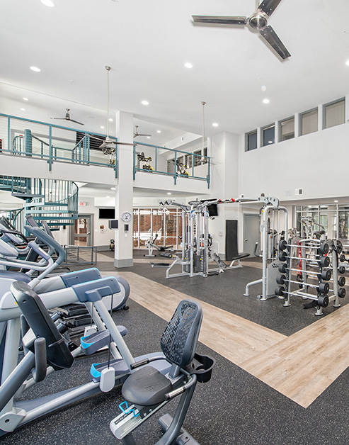 Two story fitness center with ceiling fans, wall mounted TVs and variety of workout equipment at MAA Acklen luxury apartments in Nashville, TN