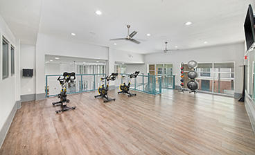 Fitness center second floor level with exercise bikes, weighted medicine ball and yoga ball rack next to large windows in natural light at MAA Acklen luxury apartments in Nashville, TN