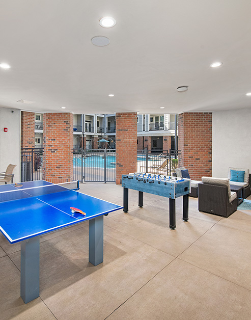 Poolside game area with table tennis and foosball table on tile flooring at MAA Acklen luxury apartments in Nashville, TN