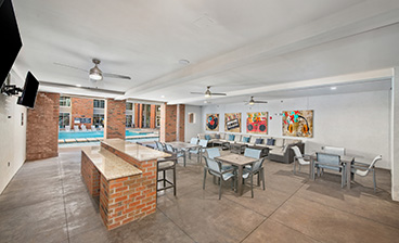 Poolside lounge area with ceiling fans, wall mounted TV next to a brick bar top counter with multiple siting areas at MAA Acklen luxury apartments in Nashville, TN