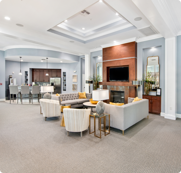Community clubhouse with large open lounge area with TV and fireplace next to open kitchen and bar at MAA Bellevue luxury apartments in Nashville, TN