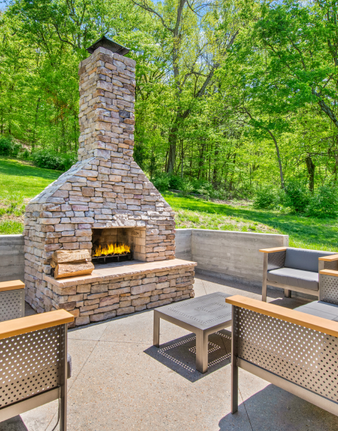 Outside common area with a large brick fireplace and stainless-steel chairs and side table at MAA Bellevue luxury apartments in Nashville, TN