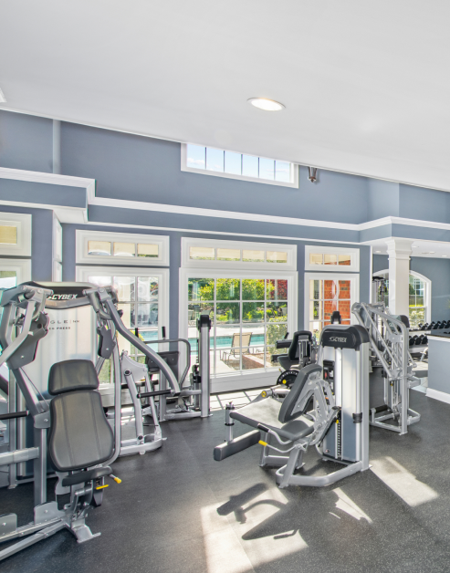 Fitness center with a variety of workout equipment next to large picture windows with a pool view at MAA Bellevue luxury apartments in Nashville, TN