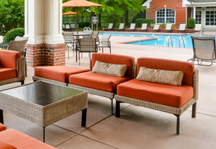 Poolside covered patio with multiple sitting areas with orange cushions at MAA Bellevue luxury apartments in Nashville, TN