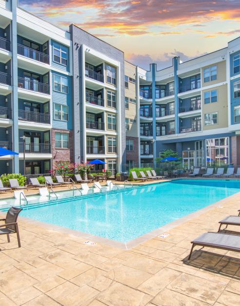 Resort-style swimming pool with a sundeck, surrounded by lounge chairs situated next to the apartment complex at MAA Charlotte Ave luxury apartments in Nashville, TN