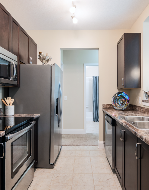 Stylish kitchen with ceiling track lighting, dark brown cabinets and stainless-steel appliances with tile floors at MAA Cool Spring luxury apartments in Franklin, TN