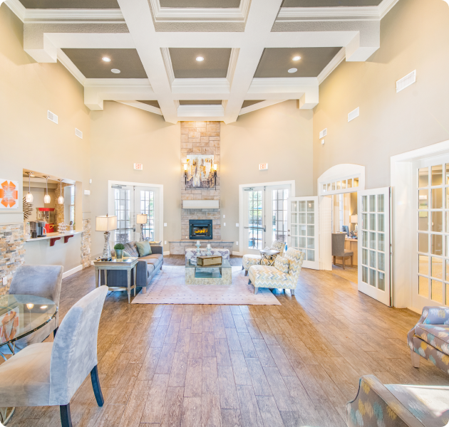 Community clubhouse great room with wood beam high ceiling, double French doors, brick fireplace and multiple siting areas on wood floors at MAA Kennesaw Farms luxury apartments in Gallatin, TN