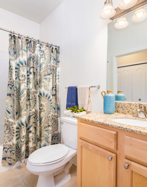 Bathroom with sleek light fixtures above vanity mirror and sink with light brown cabinets on tile floors at MAA Kennesaw Farms luxury apartments in Gallatin, TN